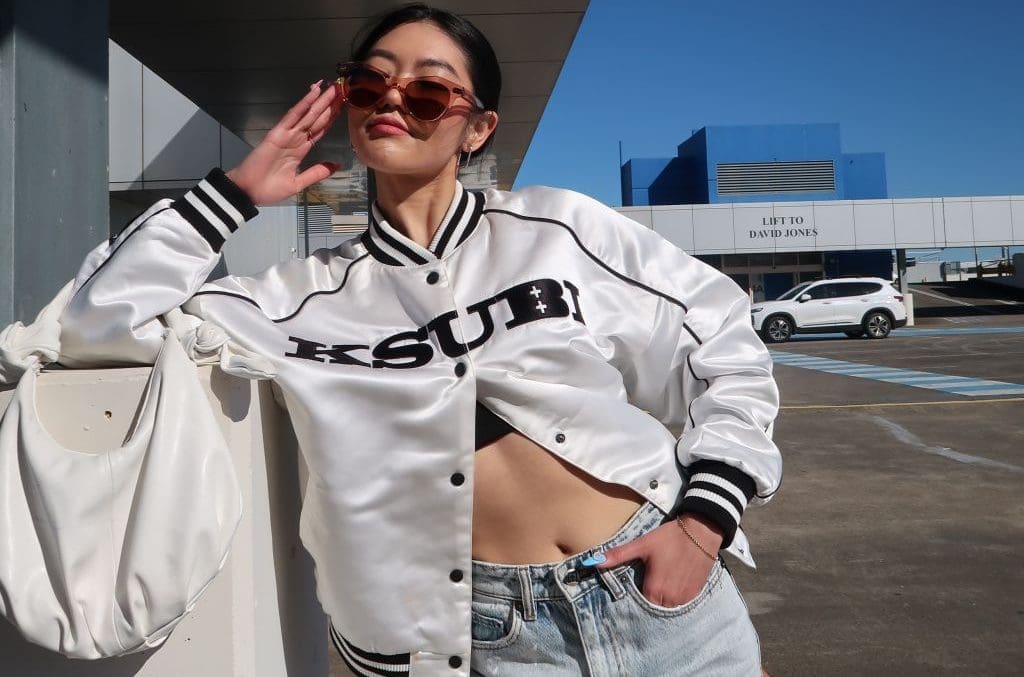 woman in white varsity and blue jeans